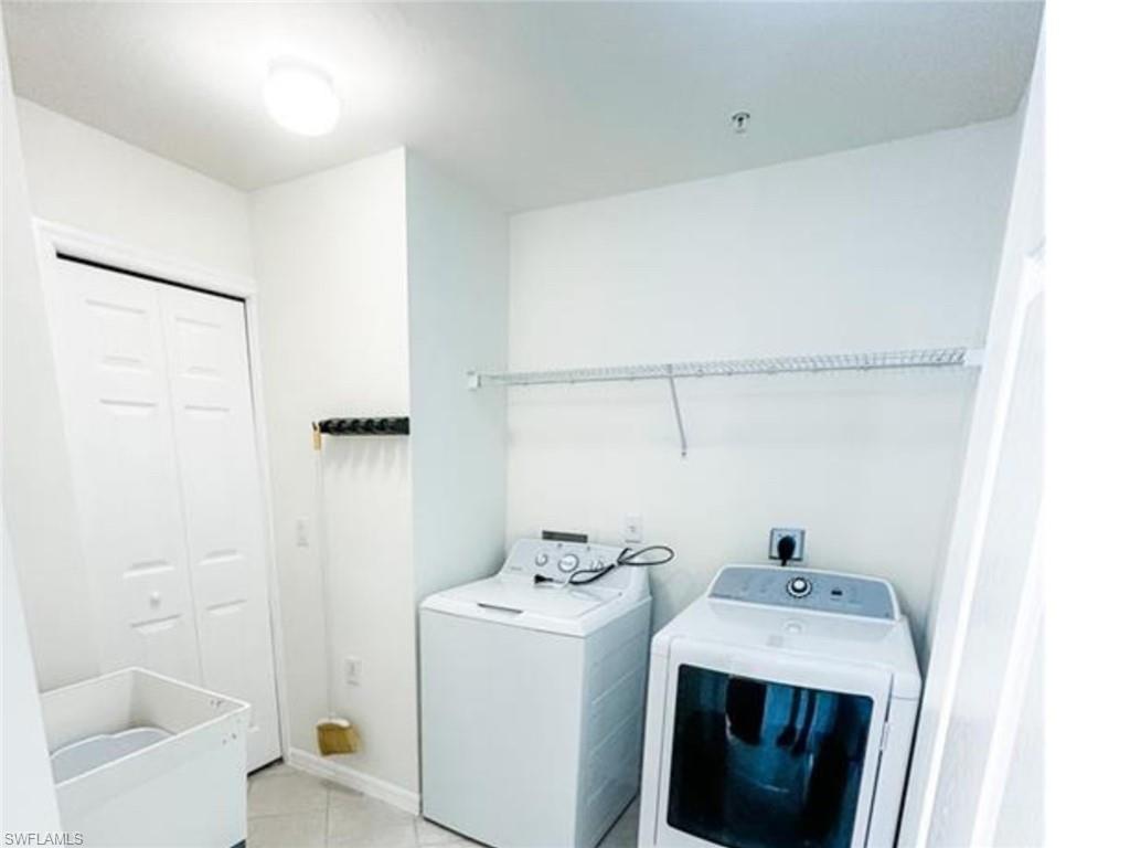 Laundry area with laundry area, washing machine and dryer, and light tile patterned floors