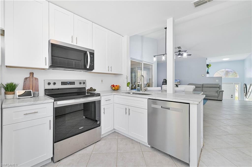 Kitchen featuring appliances with stainless steel finishes, a sink, light countertops, light tile patterned floors, and visible vents