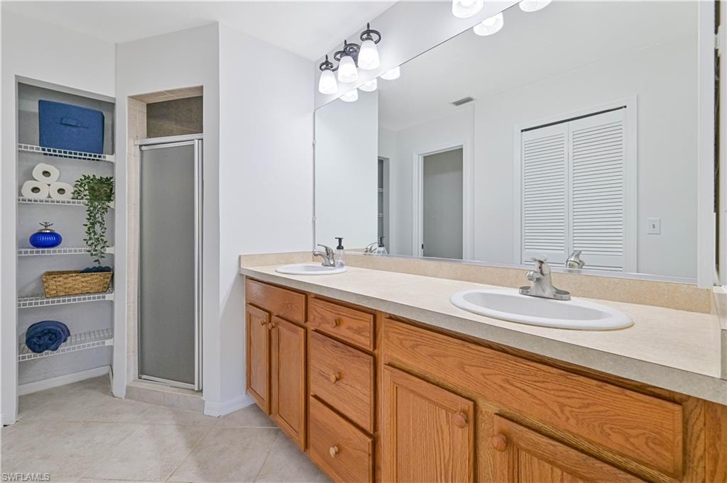 Full bath with double vanity, a sink, and a stall shower