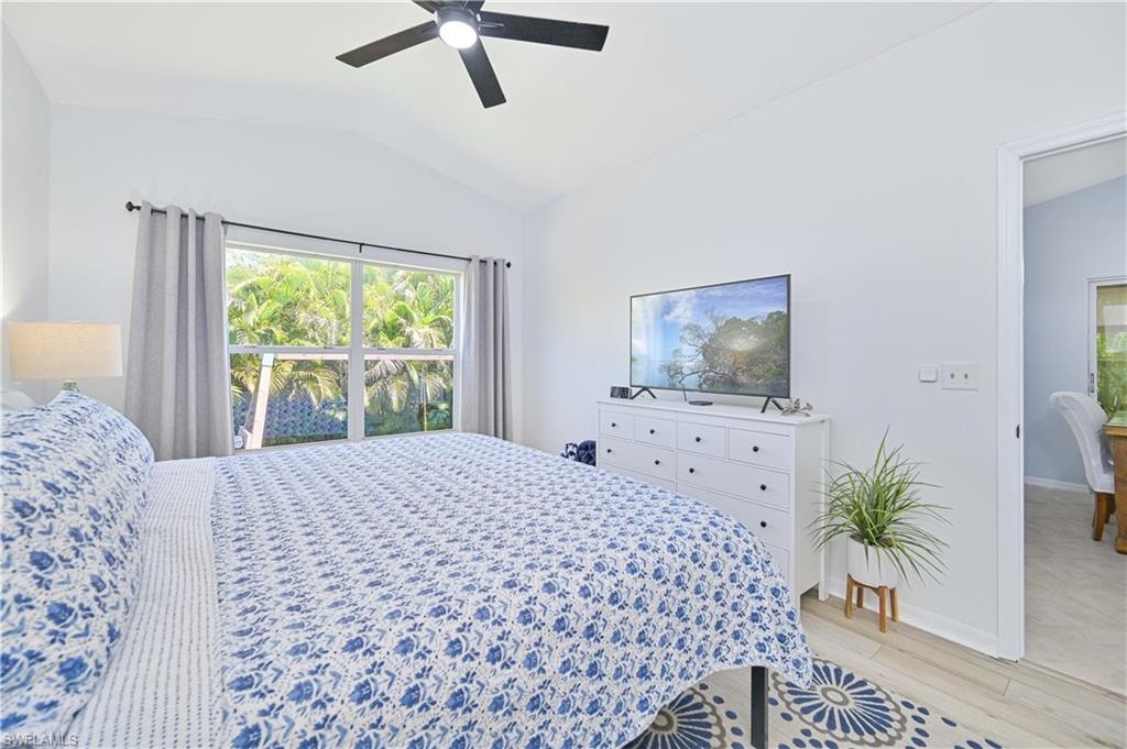 Bedroom with baseboards, a ceiling fan, vaulted ceiling, and light wood-type flooring