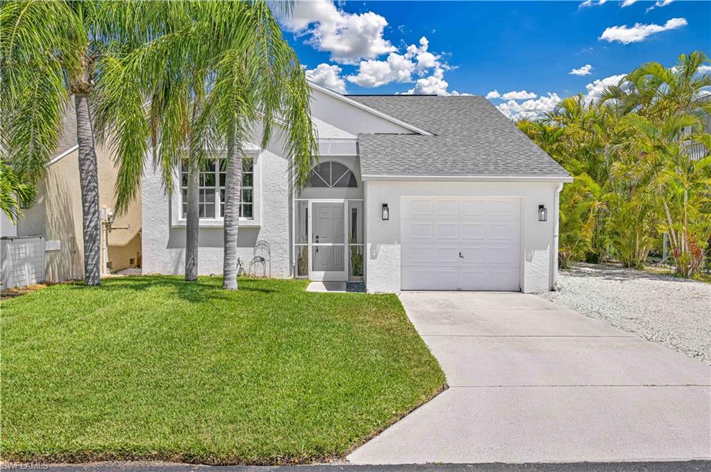 View of front of property with stucco siding, concrete driveway, a front yard, and a garage