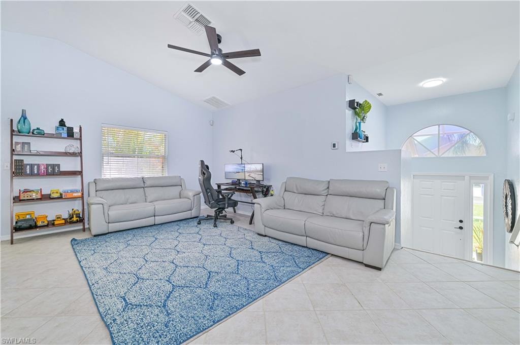 Living room with visible vents, a ceiling fan, light tile patterned floors, and high vaulted ceiling