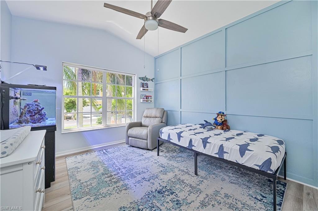 Bedroom featuring baseboards, vaulted ceiling, ceiling fan, and light wood-type flooring