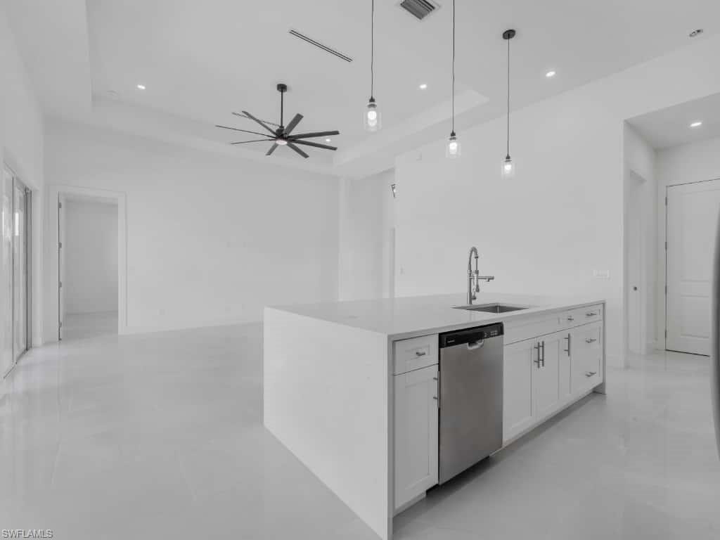Kitchen with stainless steel appliances, white cabinetry, light countertops, recessed lighting, and decorative light fixtures