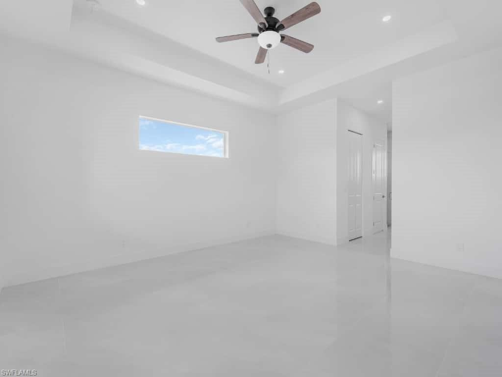 Unfurnished room featuring a raised ceiling, recessed lighting, and ceiling fan