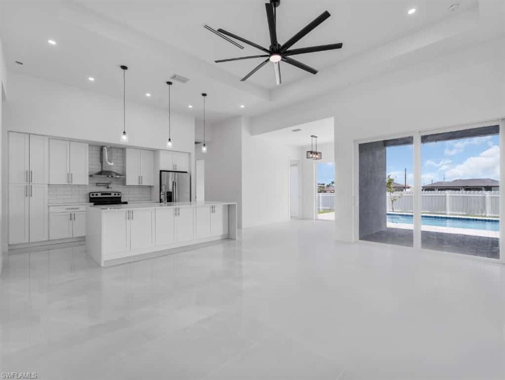 Kitchen with open floor plan, backsplash, white cabinetry, wall chimney exhaust hood, and stainless steel refrigerator with ice dispenser