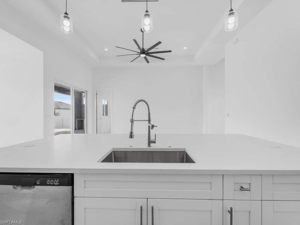 Unfurnished living room featuring a raised ceiling, a ceiling fan, a chandelier, and recessed lighting