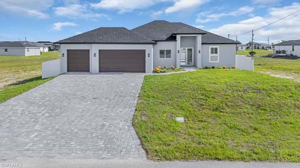 View of front of house with stucco siding, a garage, decorative driveway, a front lawn, and roof with shingles