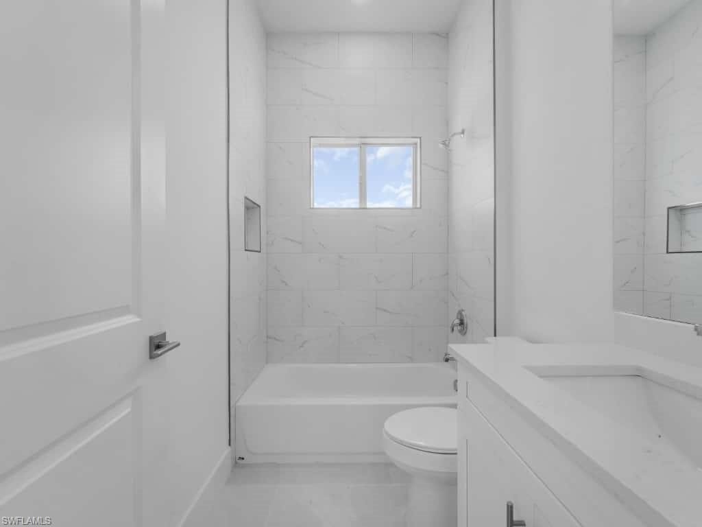 Kitchen with white cabinets, stainless steel dishwasher, hanging light fixtures, light countertops, and a center island with sink