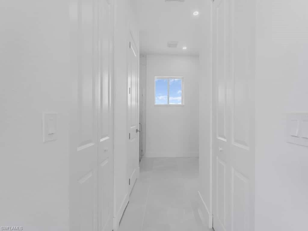 Hallway featuring a tray ceiling, recessed lighting, and tile patterned floors