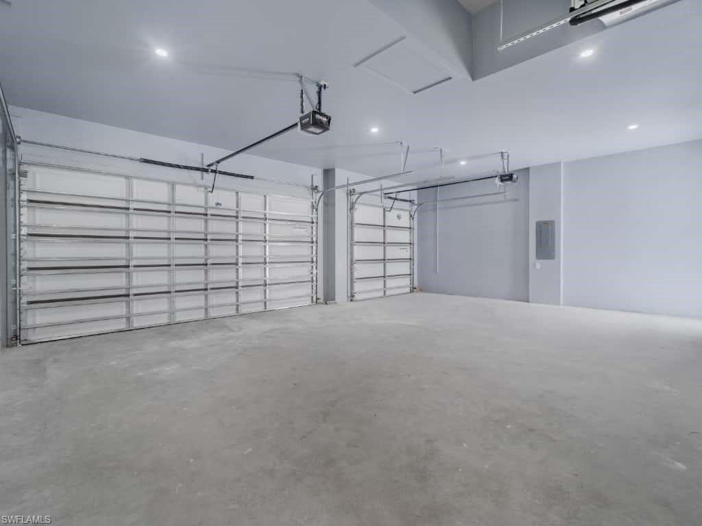 Garage featuring recessed lighting, a garage door opener, and electric panel