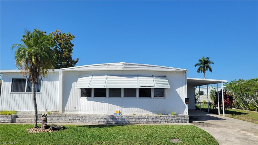 Manufactured / mobile home featuring driveway, a front yard, and an attached carport