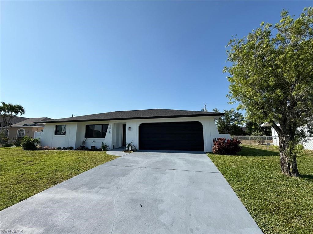 Ranch-style home with a front lawn, driveway, fence, and a garage