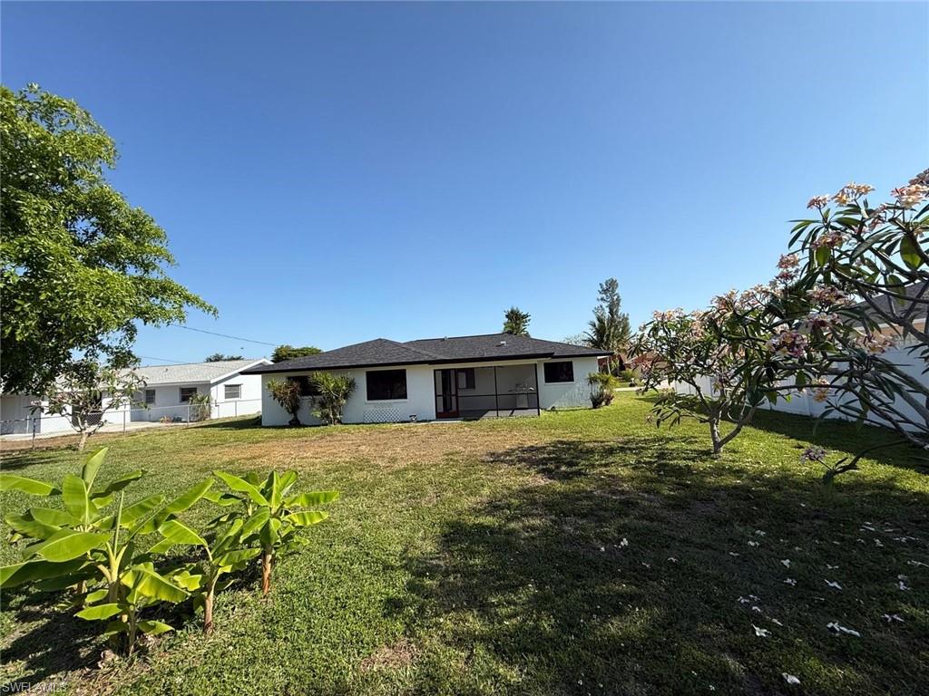 Rear view of property with a yard and fence