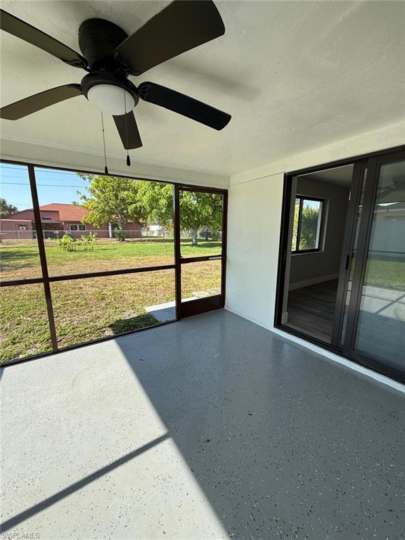 Unfurnished sunroom featuring a ceiling fan
