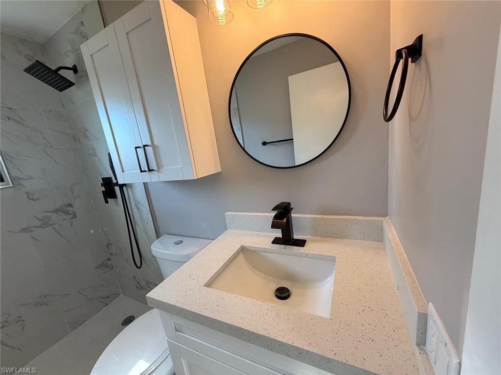 Bathroom featuring a stall shower, vanity, and toilet