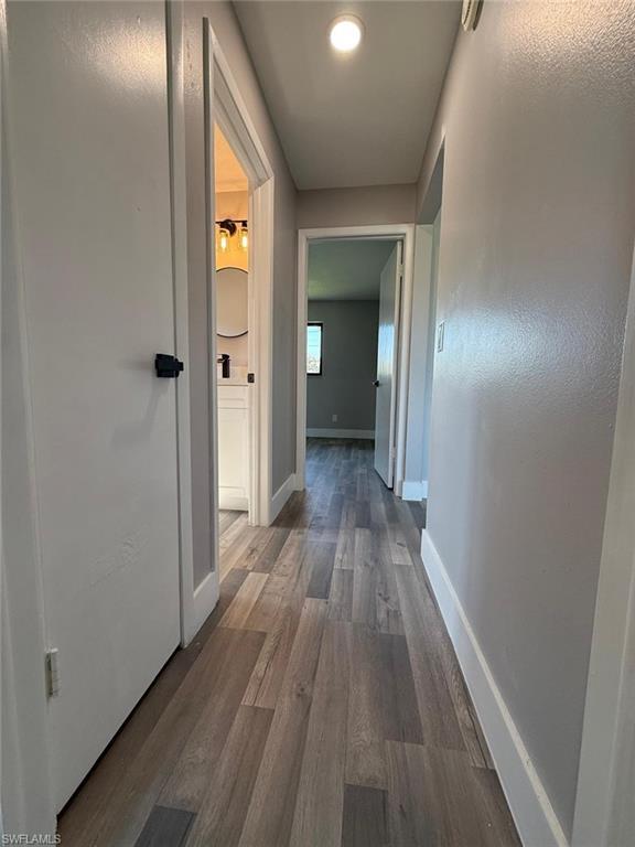 Corridor featuring baseboards and dark wood finished floors