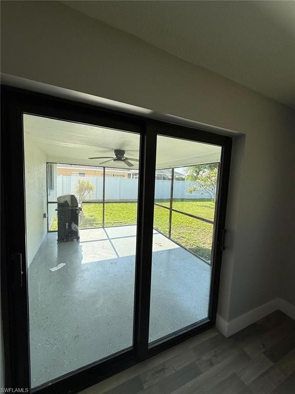 Doorway featuring a ceiling fan, wood finished floors, and baseboards