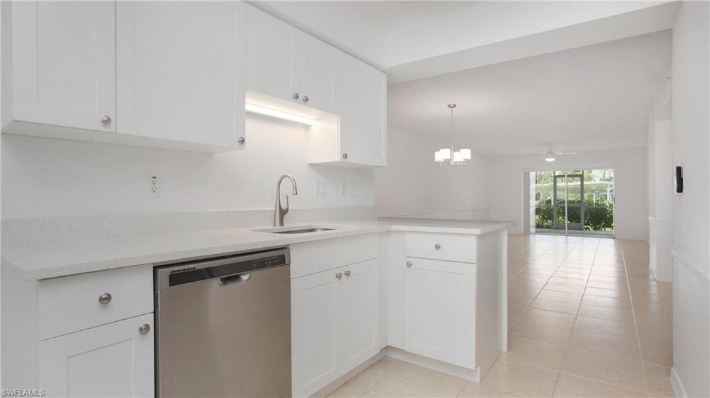 Kitchen featuring stainless steel dishwasher, a sink, light countertops, white cabinets, and open floor plan