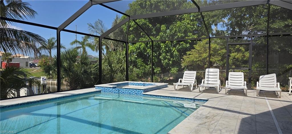 View of pool with a patio area, a pool with connected hot tub, and glass enclosure