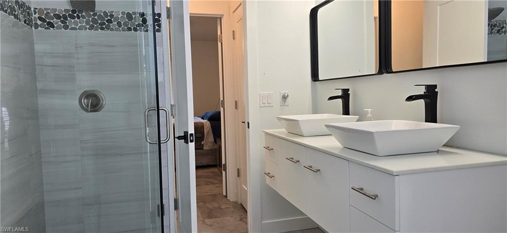 Full bath featuring a stall shower, marble finish flooring, double vanity, and ensuite bathroom