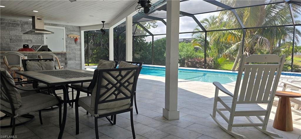 Swimming pool with exterior kitchen, a patio, outdoor dining space, and glass enclosure