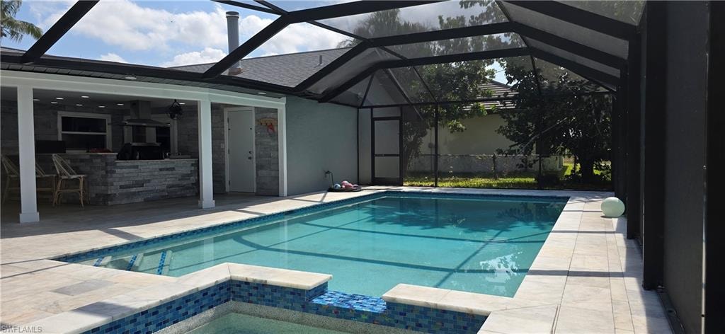 Swimming pool featuring a patio, glass enclosure, and an in-ground hot tub