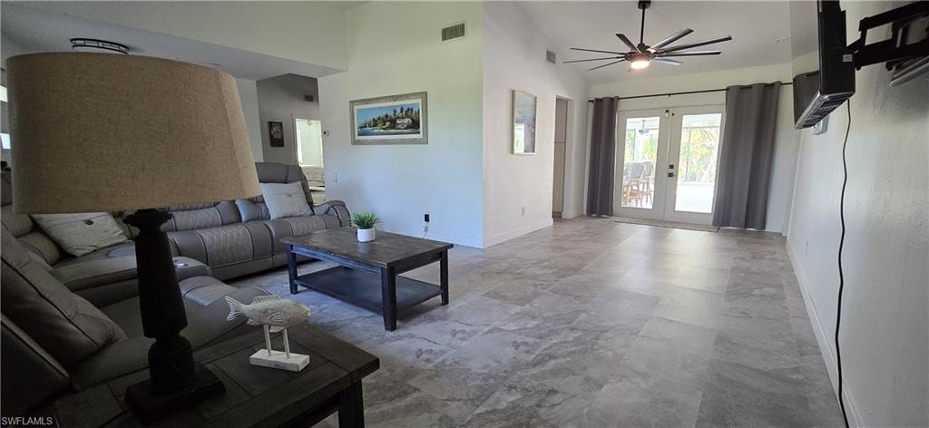 Living area with ceiling fan, baseboards, a towering ceiling, and french doors