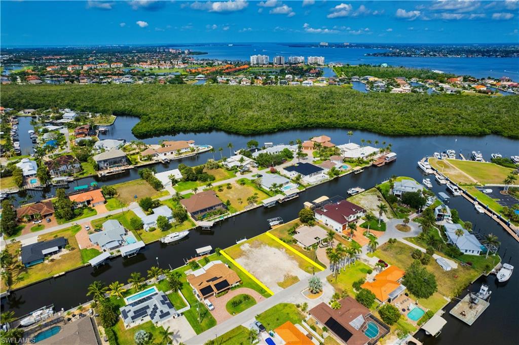 Aerial view of property's location featuring a large body of water, nearby suburban area, and property parcel outlined