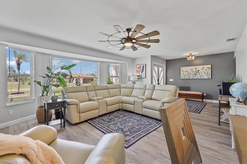 Living area with plenty of natural light, baseboards, a ceiling fan, and light wood-style floors