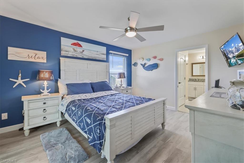 Bedroom featuring wood finished floors, baseboards, ceiling fan, and ensuite bath