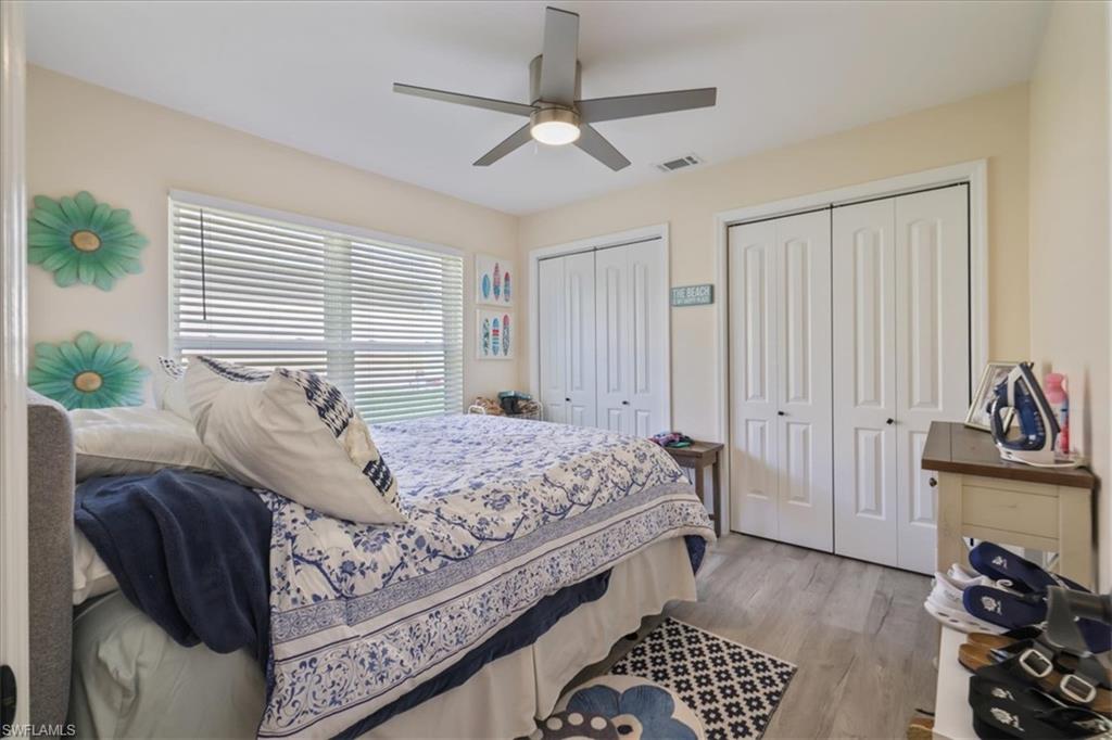 Bedroom featuring multiple closets, light wood-type flooring, and ceiling fan