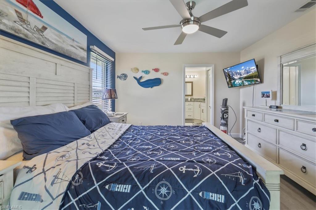 Bedroom with ensuite bath, wood finished floors, ceiling fan, and baseboards