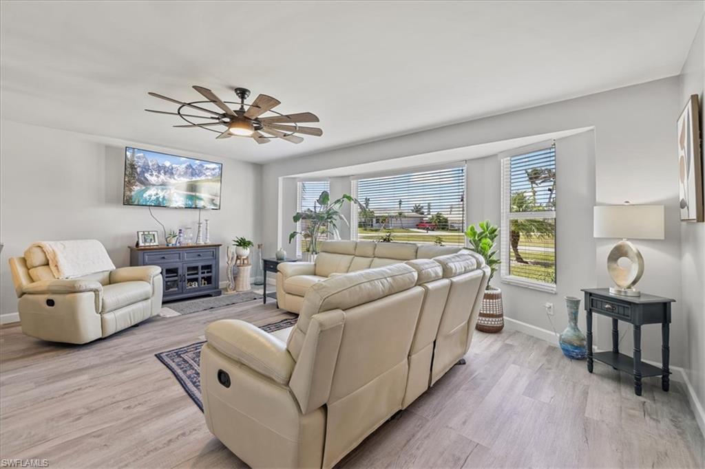 Living room with baseboards, light wood-type flooring, and a ceiling fan