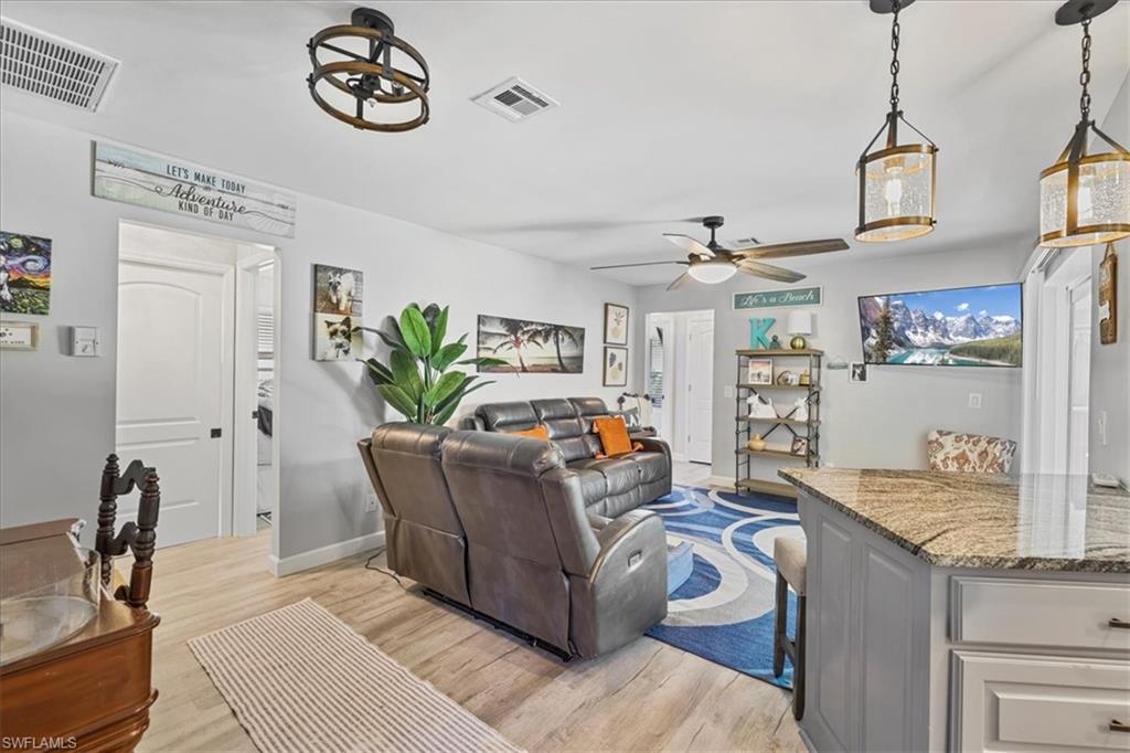 Living room with a ceiling fan, light wood-style floors, and baseboards