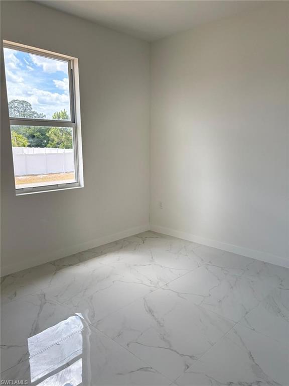 Empty room featuring baseboards and marble finish floors