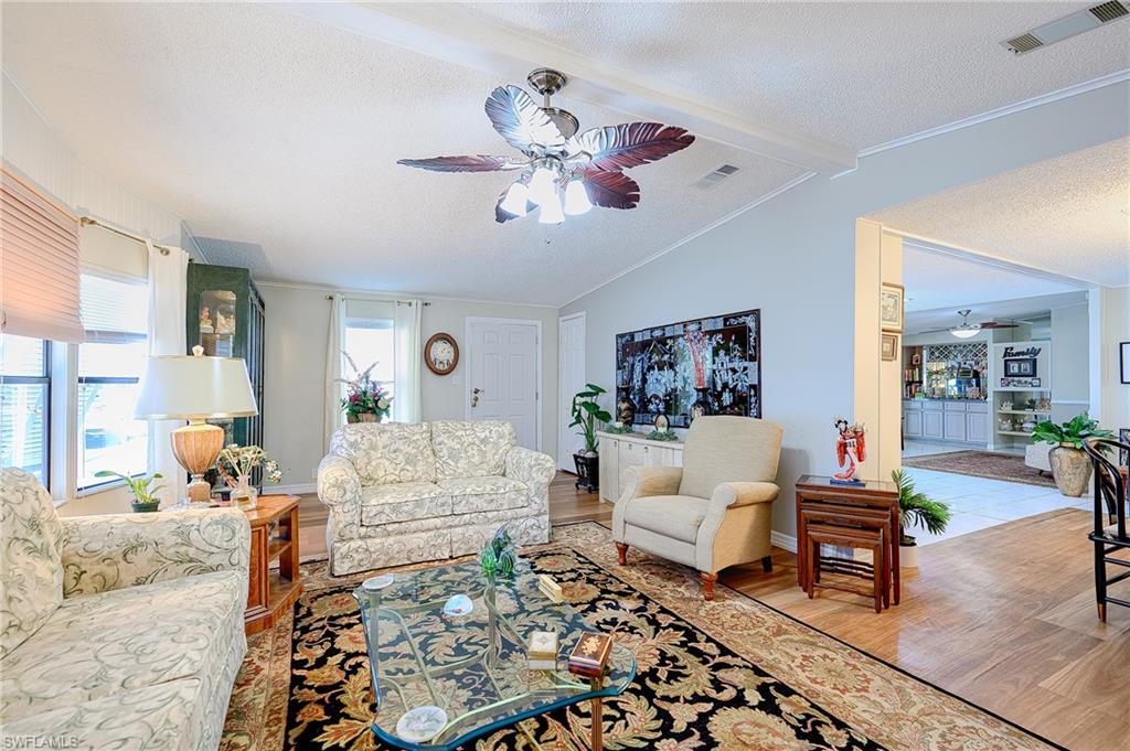 Living area with ceiling fan, wood finished floors, a textured ceiling, baseboards, and crown molding