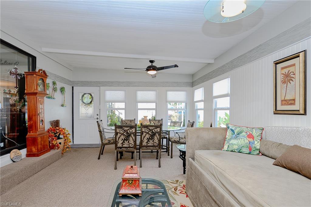 Carpeted living area featuring beam ceiling and a ceiling fan