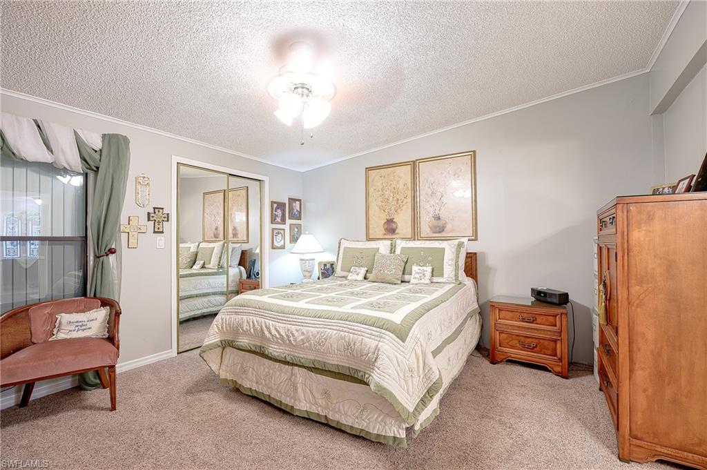 Bedroom with light colored carpet, crown molding, a textured ceiling, a closet, and ceiling fan
