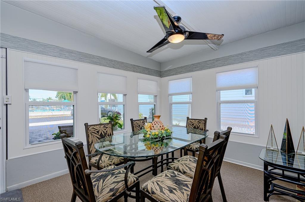 Dining room featuring dark colored carpet, plenty of natural light, a ceiling fan, baseboards, and lofted ceiling