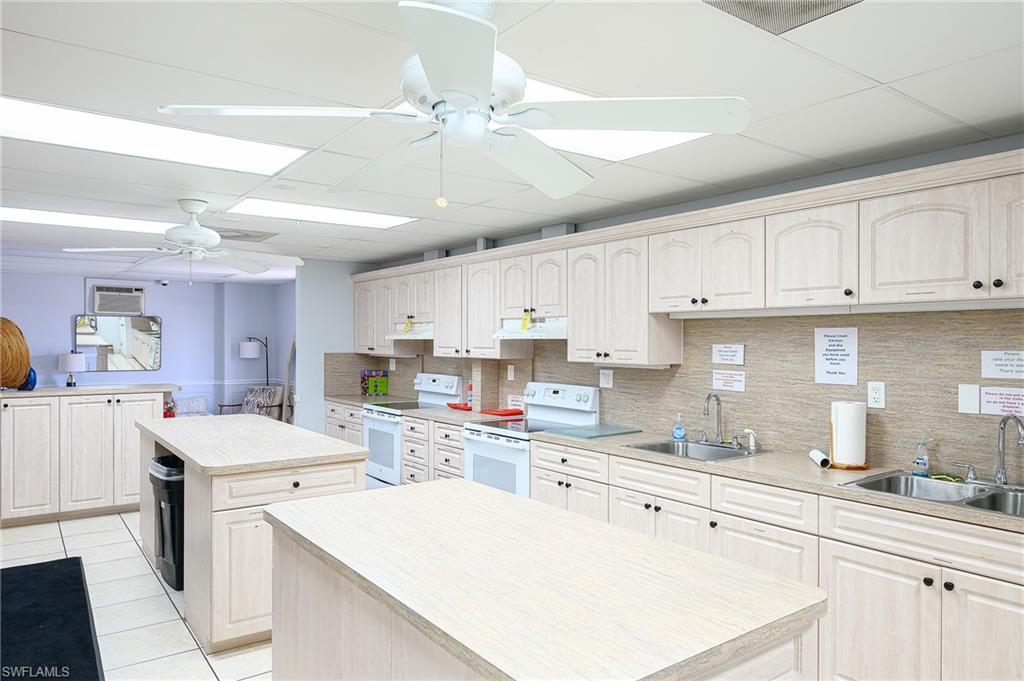Community room Kitchen featuring white electric stove, a center island, a ceiling fan, and a sink