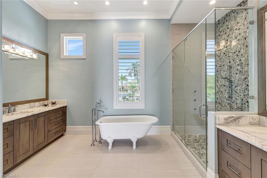 Master Bathroom with a stall shower, vanity, a freestanding bath, tile patterned floors, and baseboards