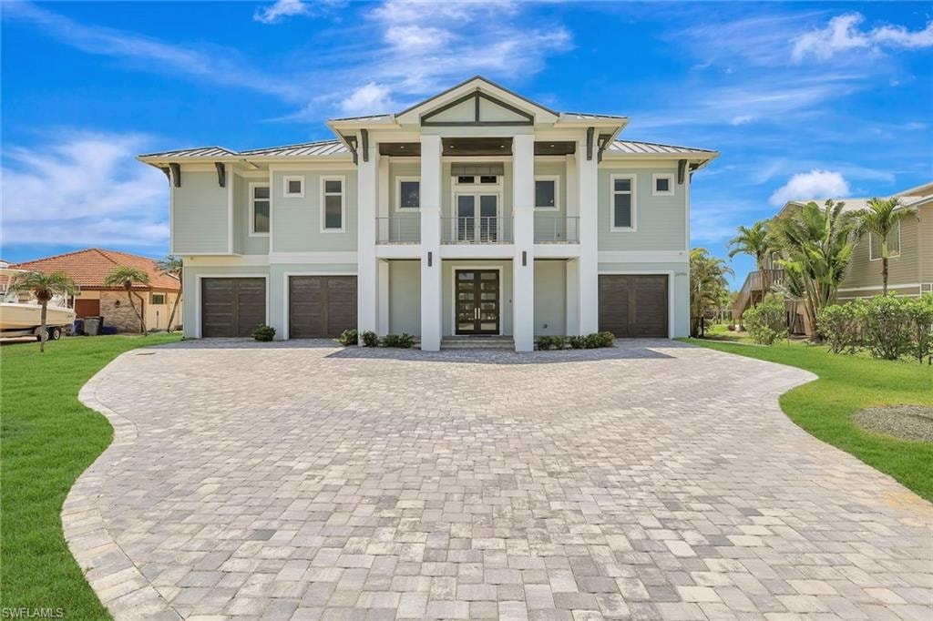 View of front of house with a garage, a standing seam roof, and decorative driveway