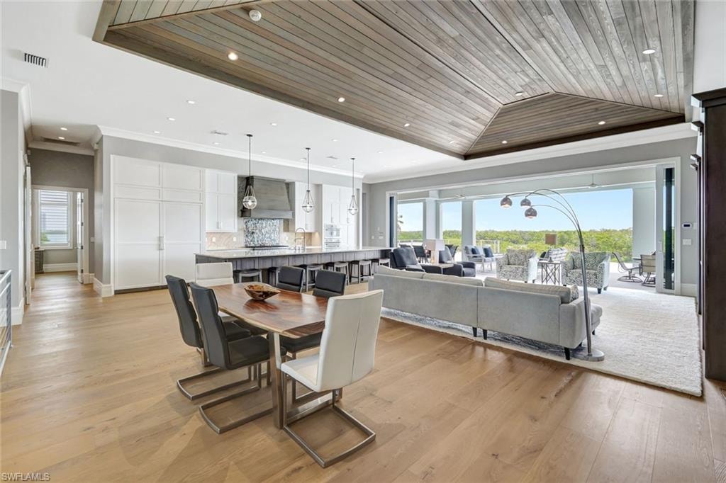 Dining area with ornamental molding, wood ceiling, healthy amount of natural light, a tray ceiling, and baseboards