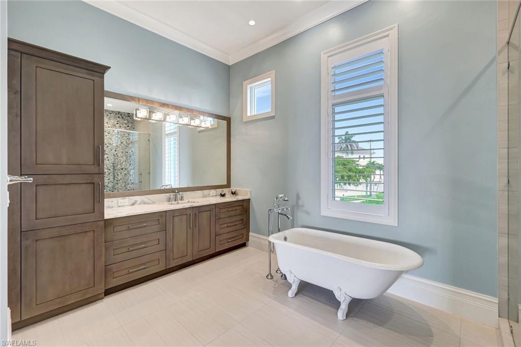 Master Bathroom with a shower stall, a freestanding tub, vanity, baseboards, and crown molding