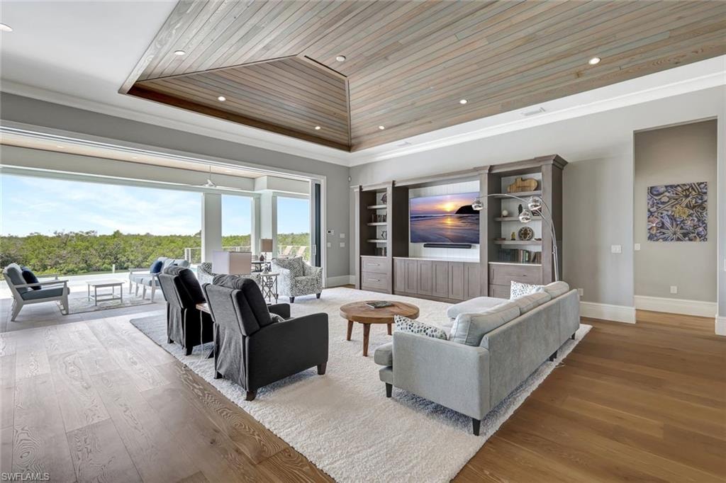 Living area featuring wood ceiling, baseboards, wood finished floors, a tray ceiling, and recessed lighting