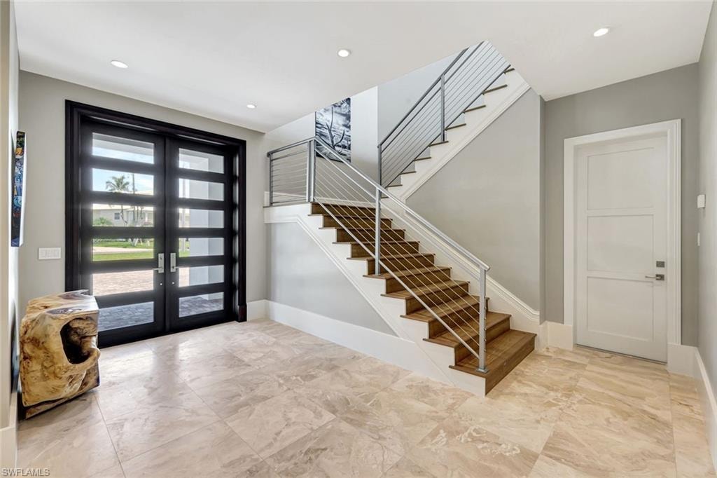 Entrance foyer featuring french doors, stairway, marble finish floors, baseboards, and recessed lighting