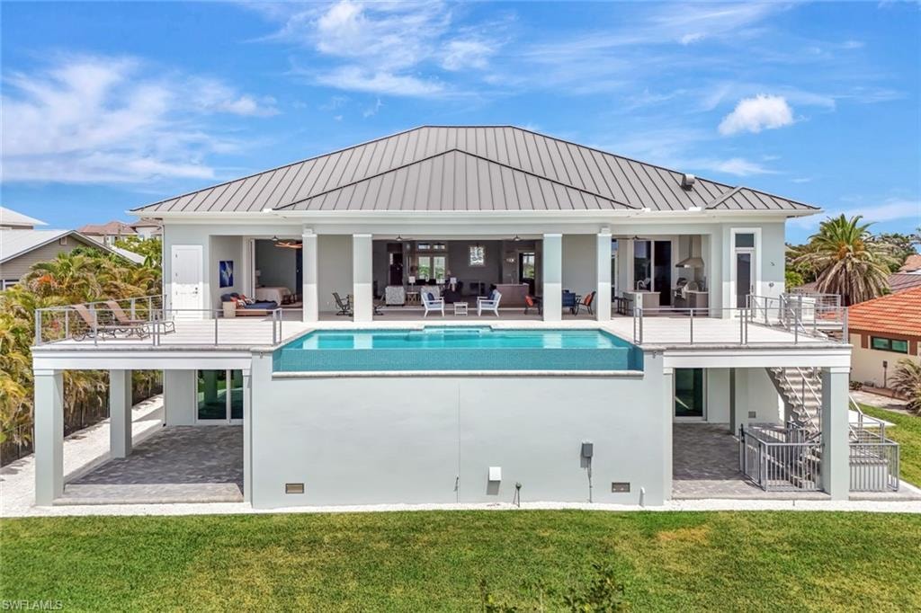 Rear view of house featuring outdoor lounge area, a standing seam roof, a patio, and stairs