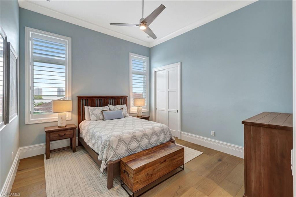 Guest 1 Bedroom featuring light wood-style flooring, baseboards, crown molding, and a ceiling fan