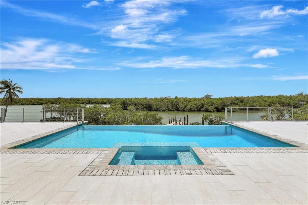View of pool with a patio, fence, and a pool with connected hot tub